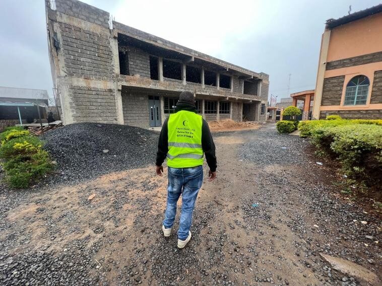 Chaschase site supervisor walking towards the unfinished AIPCA Church Hall building