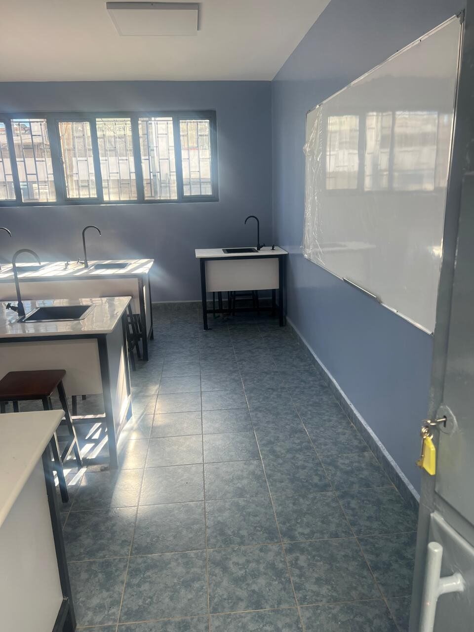 Laboratory classroom with whiteboard, workstations and tiled flooring