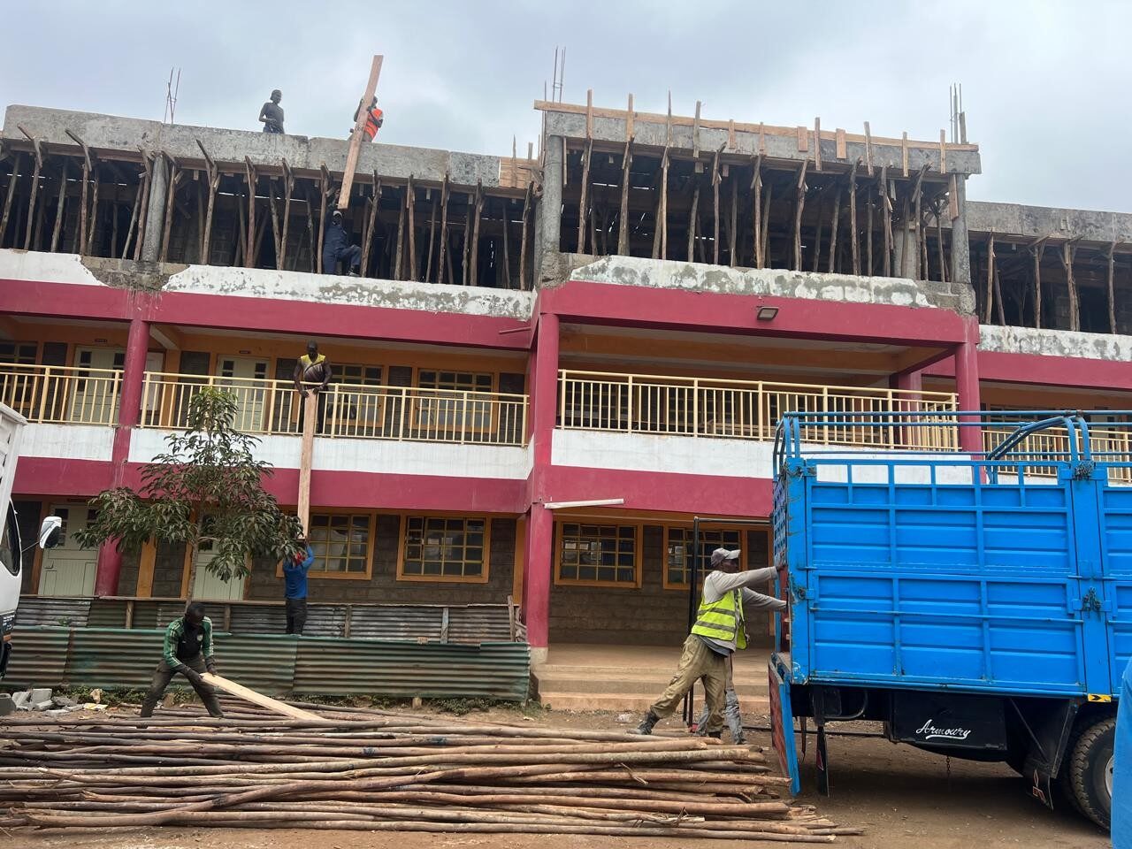 Smiling Junior School construction site with workers and delivery truck